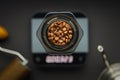 Aeropress coffee maker with scales, coffee grinder and kettle on a black background top view. Aeropress with coffee beans in focus