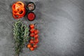 An aesthetic arrangement of sprigs of fragrant rosemary, three rings of red pepper, a branch of cherry tomatoes and two black cups Royalty Free Stock Photo