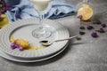 Aesthetic composition. Purple flowers and colorful fabric on a light table background. A plate with milk and petals.