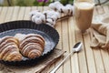 Aesthetic French breakfast - crust fresh croissant with cup of latte at the terrace. Cotton decoration. Selective focus