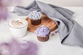 Aesthetic french dessert - cupcakes and coffee cup among lilac flowers. Guilty pleasure