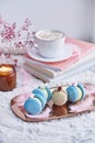 Aesthetic french dessert - macaroons among books, candle and coffee. Festive winter table setting.