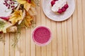 Aesthetic french raspberry tart with healthy pink strawberry smoothie on the wooden table among autumn decorations