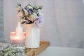 Aesthetic photo lilac flowers in a white vase a lit candle Royalty Free Stock Photo