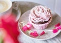 Aesthetic pink cupcake with cup of coffee. Flowers decoration. Escapism dreamy desserts. Holiday background