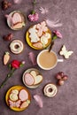 Aesthetic spring Easter background complete coffee cup, decorated glazed cookies, feathers and aster flowers flat lay