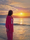 Aesthetic young woman portrait wearing pink suit on the sea shore as meets the dawn. Beautiful sunrise at the beach. Summer Royalty Free Stock Photo