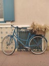 Aesthetically pleasing view of a blue bike with a basket parked in front of a cream wall