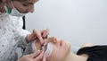 The aesthetician is applying the lash adhesive equally on the lashes