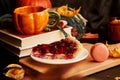 Aesthetics cozy home breakfast - cherry pie, cup of coffee in shape of pumpkin, macaroons, candle and winter cherry