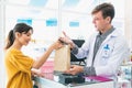 Affable pharmacist hand qualified medicine to customer in pharmacy.