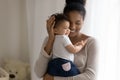 Affectionate african american mum holding little funny mixed race toddler.