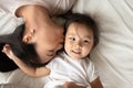 Affectionate asian ethnicity mother kissing little daughter.