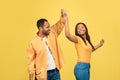 Affectionate black couple dancing, turning and spinning over yellow studio background Royalty Free Stock Photo