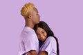 Affectionate black lady hugging her beloved boyfriend, cuddling on his chest over lilac studio background