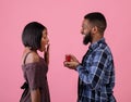 Affectionate black man proposing to his girlfriend with diamond ring on pink studio background. Valentine's Day Royalty Free Stock Photo