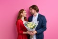 affectionate caucasian man offering his partner roses on pink background Royalty Free Stock Photo