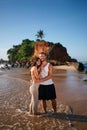 Affectionate couple hugs on sandy beach at sunrise. Romantic getaway by sea, partner embracing by ocean. Love, intimacy Royalty Free Stock Photo