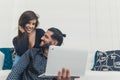 Affectionate interracial happy couple looking at each other with love. Cuban man holding a white laptop, woman sitting Royalty Free Stock Photo