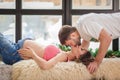 Affectionate man kissing his pregnant wife with baby letters on the belly lying on the sofa at home