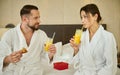 Affectionate married couple in love, taking breakfast on bed, looking at each other with tenderness. Newlyweds in bathrobes after Royalty Free Stock Photo