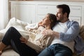 Affectionate millennial spouses resting on sofa enjoying comfort and peace