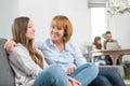 affectionate mother and daughter sitting on sofa with family in background Royalty Free Stock Photo