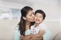 Affectionate mother holding and kissing her daughter on the couch