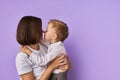 Affectionate mother and son isolated over purple background