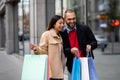 Affectionate multinational couple standing near supermarket, looking inside shopper bags, going shopping together Royalty Free Stock Photo