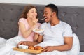 Affectionate multiracial couple having breakfast in bed, millennial lady feeding her boyfriend with cereal at home Royalty Free Stock Photo