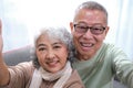 Affectionate senior Asian couple sharing warm embrace on the sofa, celebrating their enduring love and togetherness. Elderly