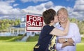 Affectionate Senior Chinese Couple In Front of House and Sign Royalty Free Stock Photo