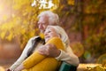 Affectionate senior couple on bench in autumn park