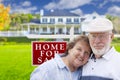 Affectionate Senior Couple Front of For Sale Sign and House