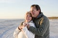 Affectionate senior couple in sweaters on beach