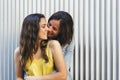 Affectionate woman kissing her happy girlfriend smiling, same sex relationship concept