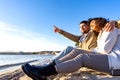 Affectionate young couple in love sitting on seashore near the ocean water next to each others looking at the sunset. Handsome man Royalty Free Stock Photo