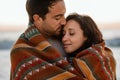 Affectionate young couple wrapped in a blanket at the beach Royalty Free Stock Photo