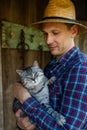 Affectionate young male farmer petting cat in barn. Royalty Free Stock Photo