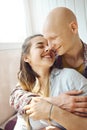 Affectionate young man with bald head embracing young woman from behind. young enamoured couple spending time together