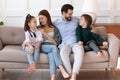Affectionate young parents relaxing on sofa, cuddling small children. Royalty Free Stock Photo