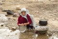 Afghan girl washes dishes in creek