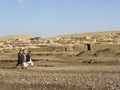 Afghans walk past traditional mud walled homes