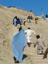 Afghan women in burqas with children climb steps