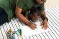 Afican american family together painting at home. Little daughter and her mother are drawing with colorful pencils Royalty Free Stock Photo