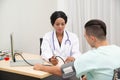 African female Doctor measuring Caucasian male patient blood with pressure Measuring. Royalty Free Stock Photo