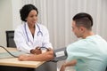 African female Doctor measuring Caucasian male patient blood with pressure Measuring. Royalty Free Stock Photo