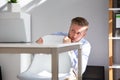 Frightened Young Businessman Hiding Behind Chair At Workplace Royalty Free Stock Photo