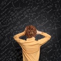 Afraid child against blackboard background with science and maths formulas Royalty Free Stock Photo